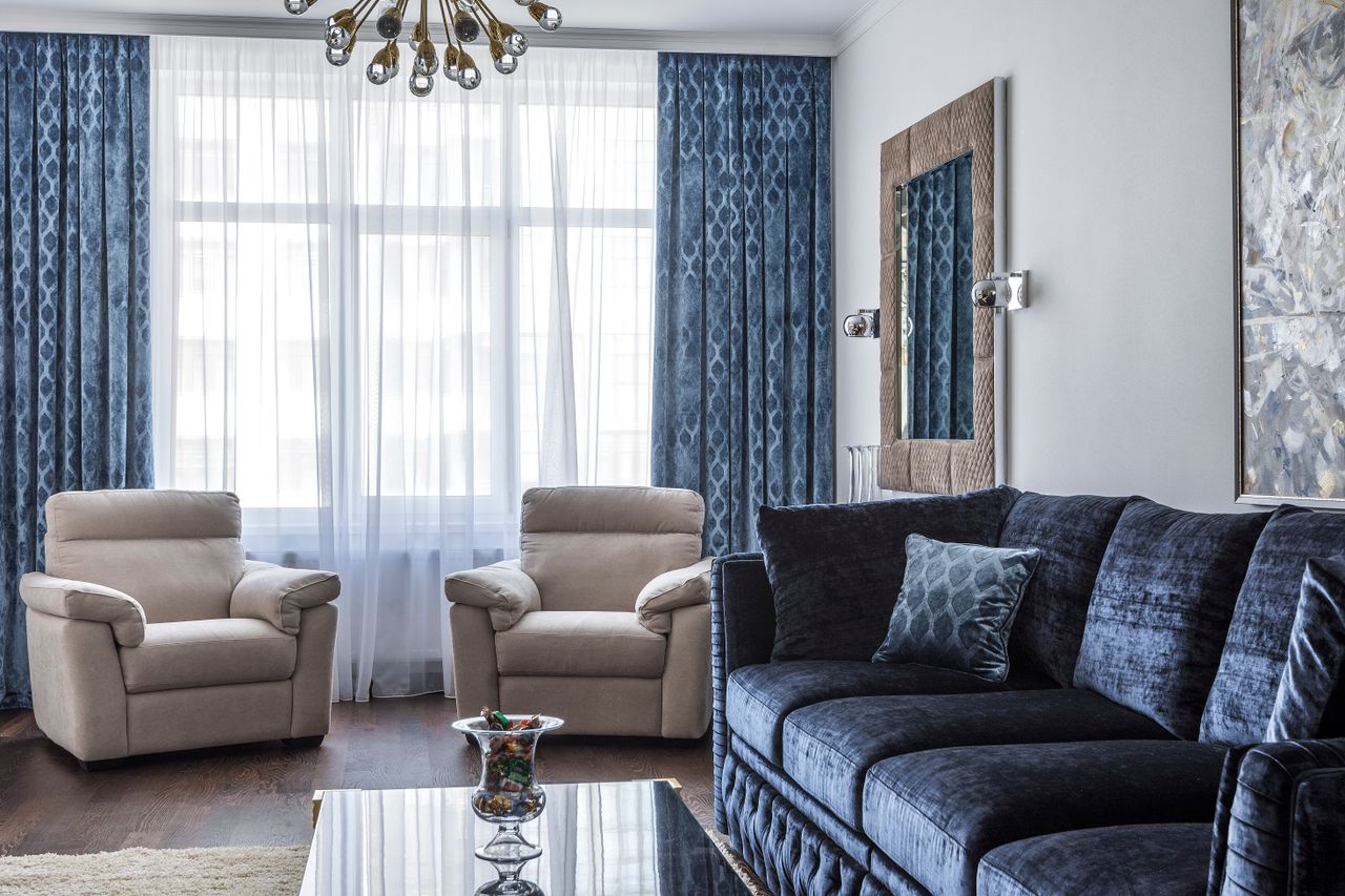 Interior of modern living room with comfortable sofa with pillows and soft armchairs